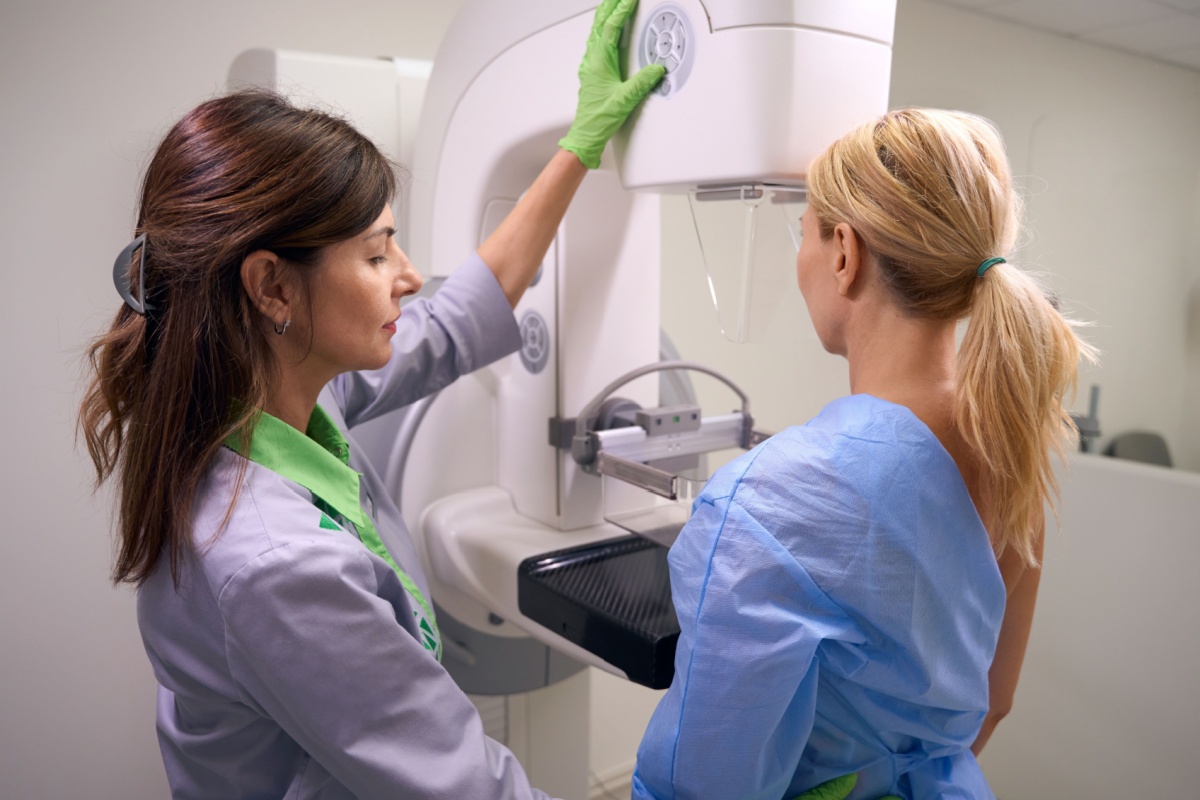 A nurse helping a woman with her mammogram screening