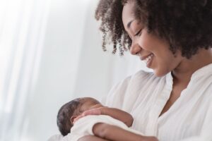 New mother holding her infant, both dressed in white