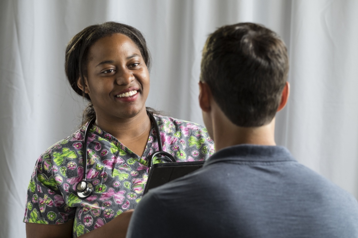 a female nurse taking the medical health history of a male patient during a physical exam