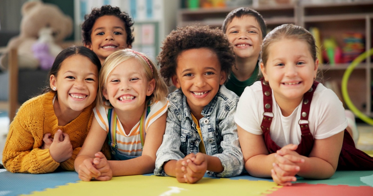 smiling kindergarteners laying on the floor of their classroom